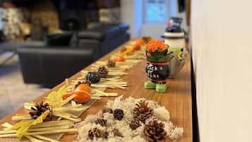 Een houten tafel met decoratieve elementen, waaronder dennenappels, een pompoen en een kleine beeldje.