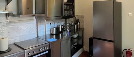 A modern kitchen with stainless steel appliances, a marble backsplash, and a pendant light.