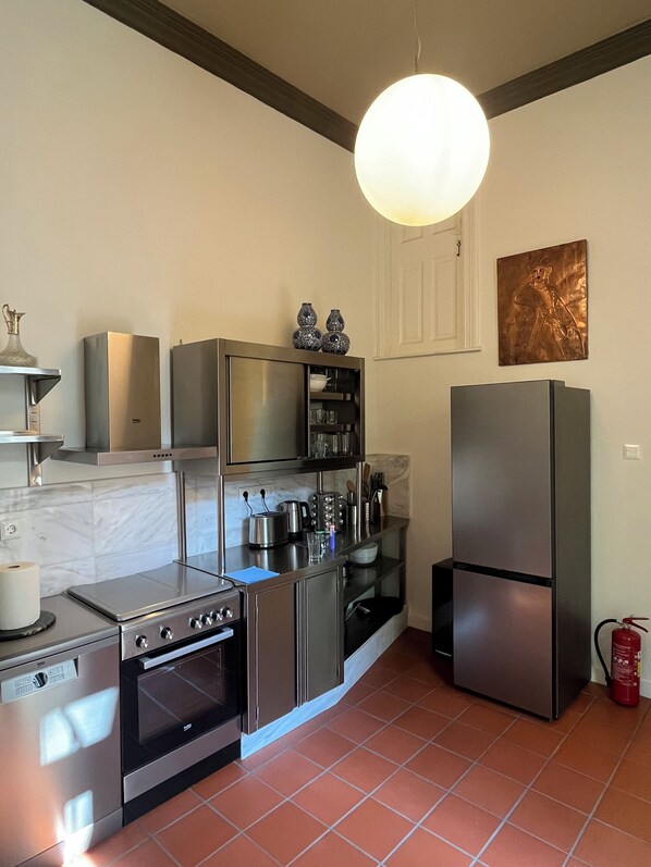 A modern kitchen with stainless steel appliances, a marble backsplash, and a pendant light. - Entire Athens Townhouse | Private Garden (Athina)