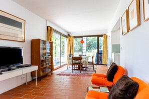 Ein modernes Wohnzimmer mit Fernseher, einer Couch und einem Essbereich.