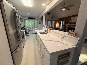 A modern kitchen with a large island, stainless steel appliances, and a stone fireplace.