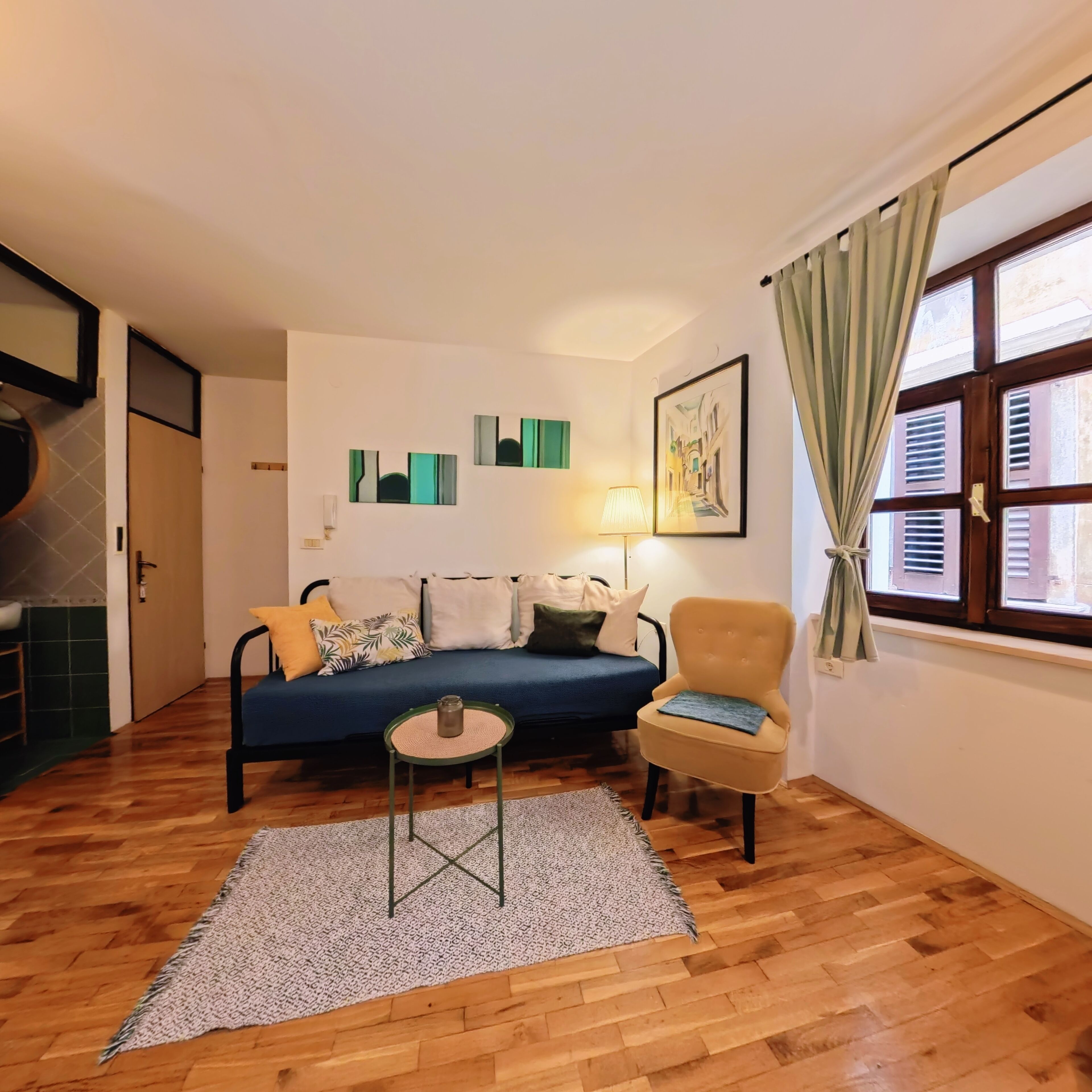 Uma sala de estar com sofá, poltrona e uma mesinha de centro com abajur.
