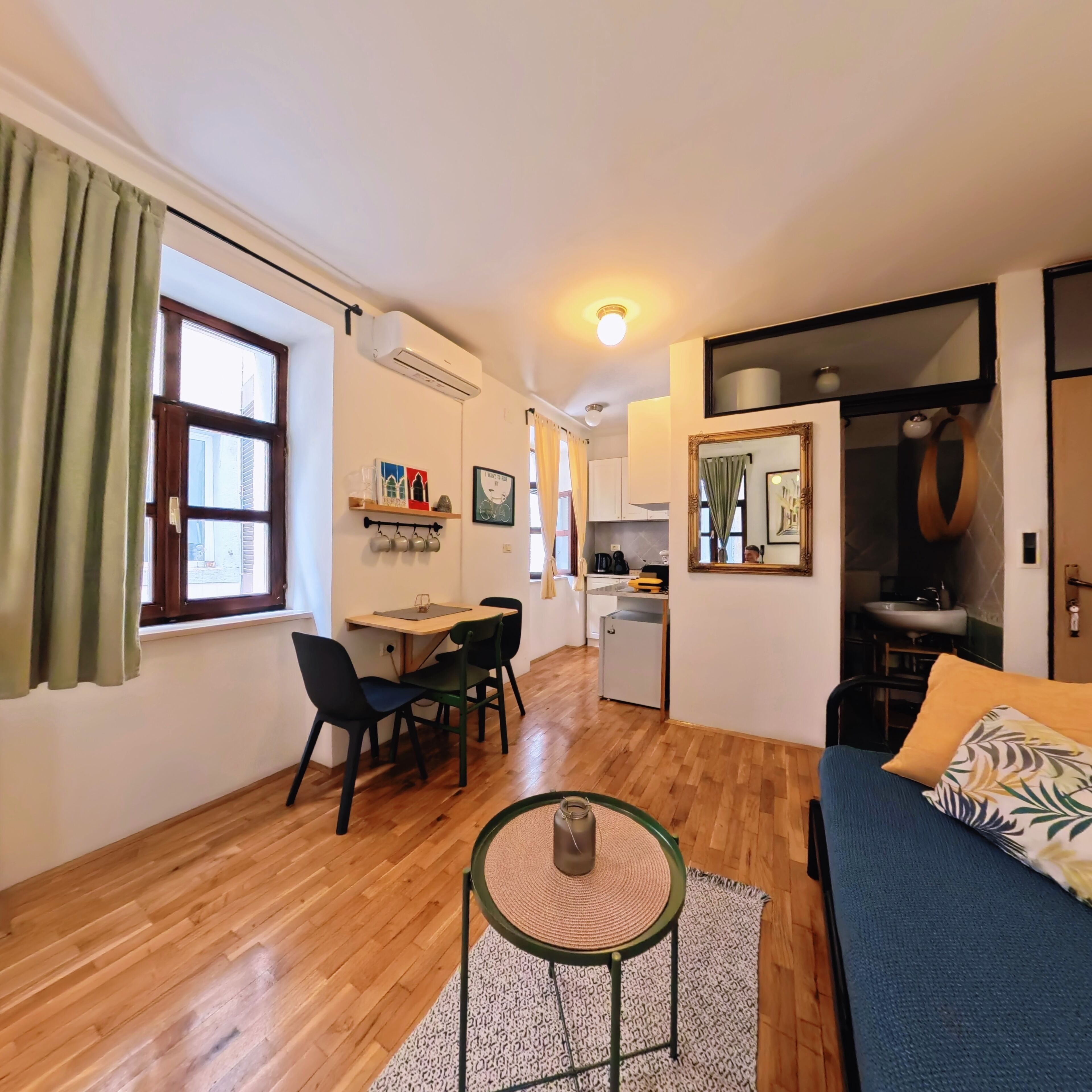 A compact living space with a dining area, kitchenette, and a sofa.