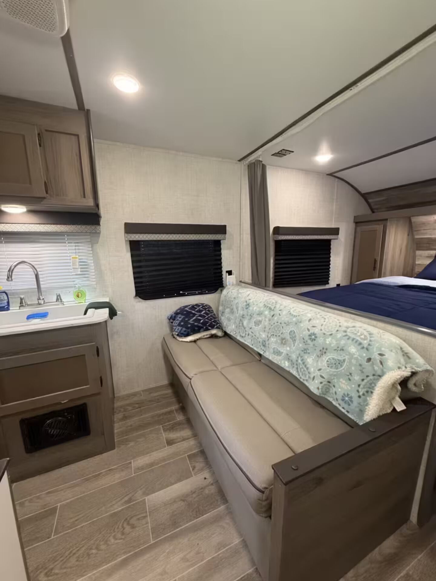 Interior compacto de una autocaravana con kitchenette, una cama y un área de estar.