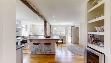 A modern kitchen with a central island, bar stools, and a built-in oven.