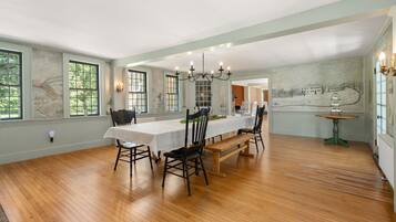 A spacious dining room with a long table, chairs, and a chandelier.