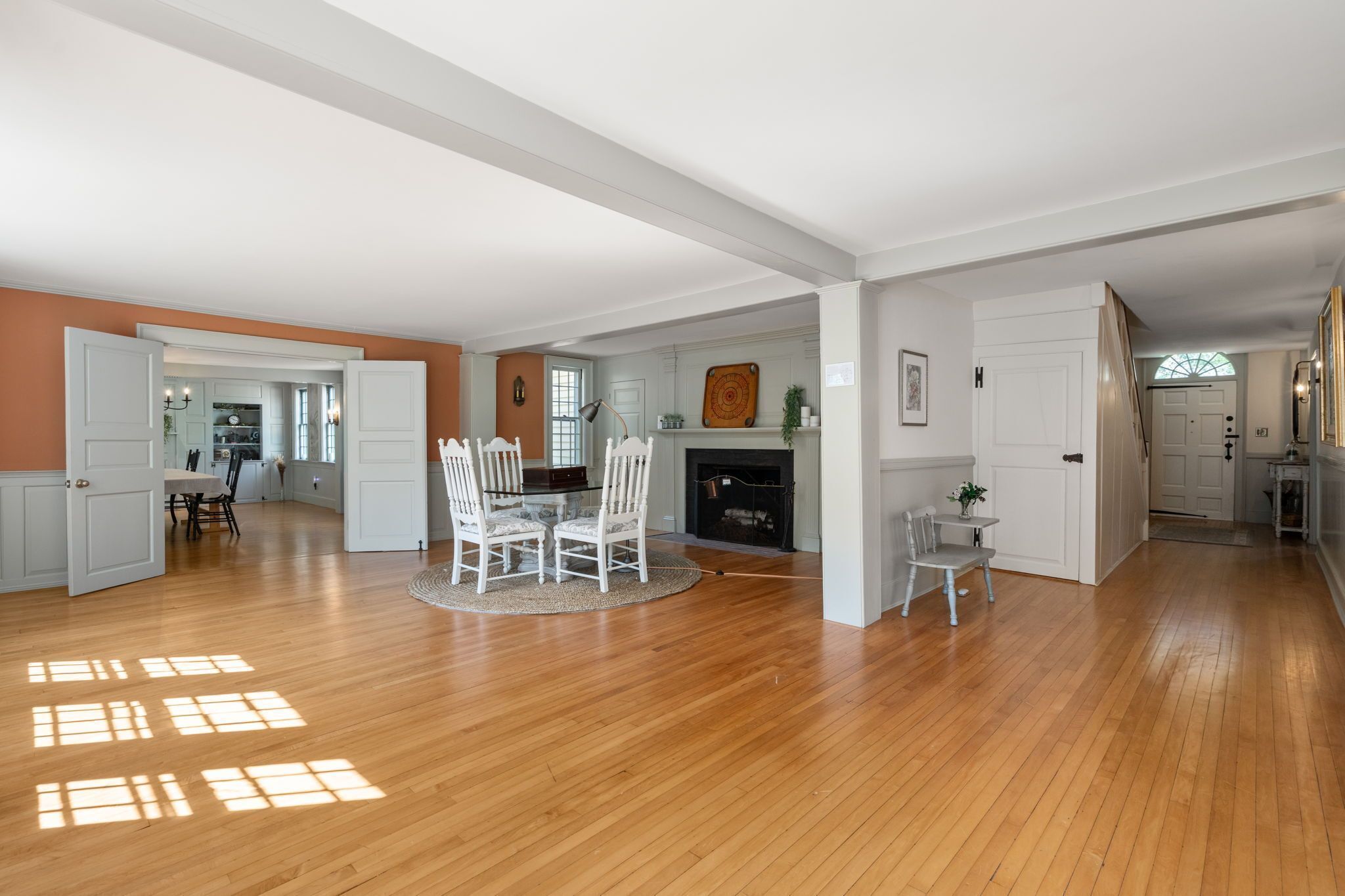 Un amplio espacio de sala con piso de madera, una mesa de comedor con sillas y una chimenea.