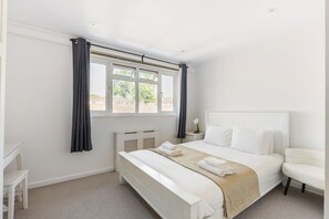 Une chambre d’hôtel avec un lit, une chaise, un bureau et une fenêtre avec des rideaux.