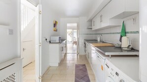 A modern kitchen with white cabinetry, a microwave, a toaster, and a kettle. - GuestReady - Charming Retreat with Private Garden (London)