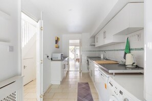 A modern kitchen with white cabinetry, a microwave, a toaster, and a kettle. - GuestReady - Charming Retreat with Private Garden (London)