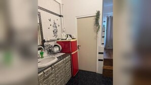 Uma cozinha compacta com pia, uma geladeira vermelha e uma porta com uma planta.