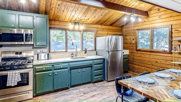 A kitchen with wooden walls, a dining table set for four, and a large window.