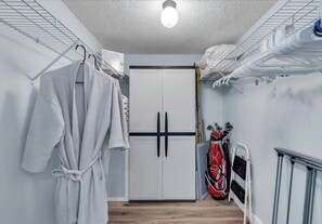 Ein kleines Zimmer mit einem Kleiderschrank, einer Wäscheständer und einer Golfausrüstung.