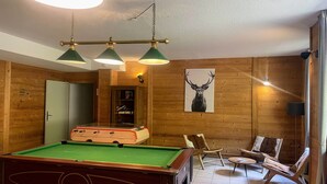 Ein Zimmer mit Poolbillard, Holzwänden, einer Deckenleuchte und einem gerahmten Bild von Tieren.