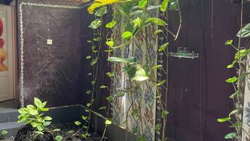 Un jardín con plantas trepadoras, fuente de agua y una estructura con techo de tejas.