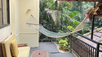 Un espacio al aire libre techado con una hamaca, un sofá y dos sillones.