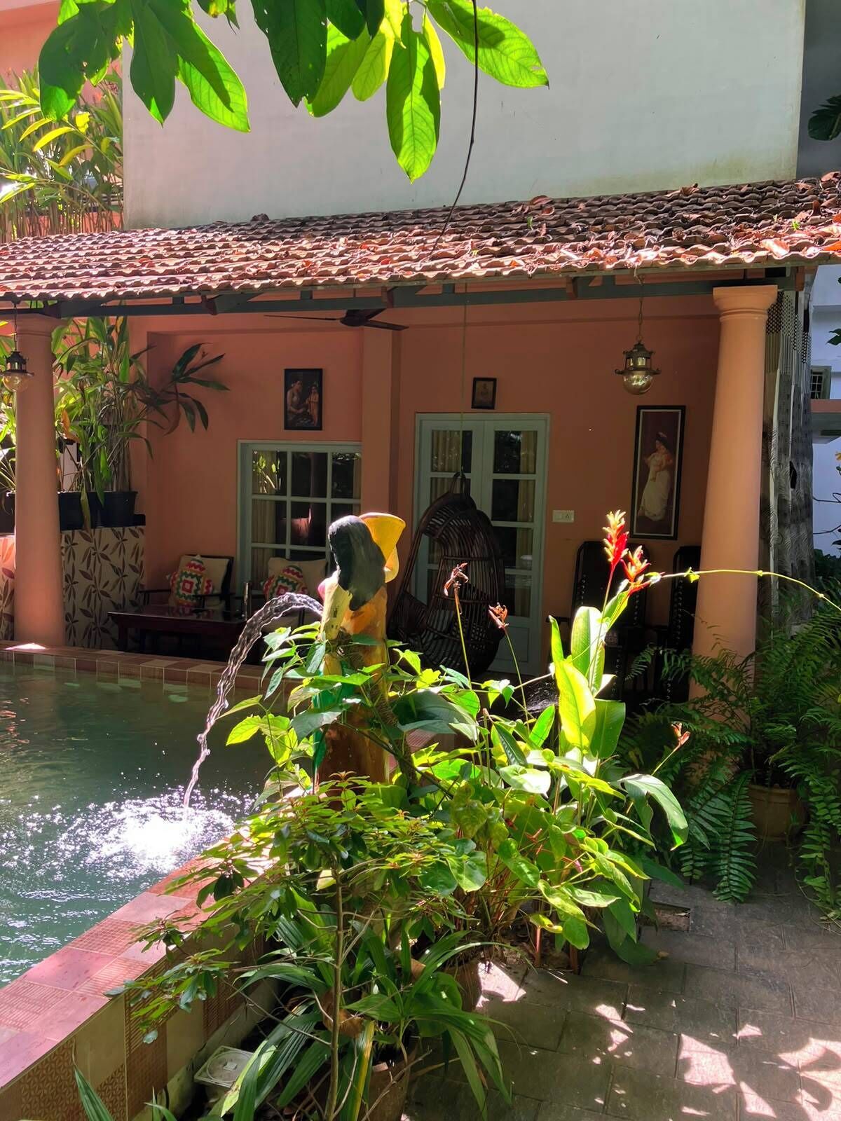 A courtyard with a water feature, potted plants, and a building with a tiled roof and columns.