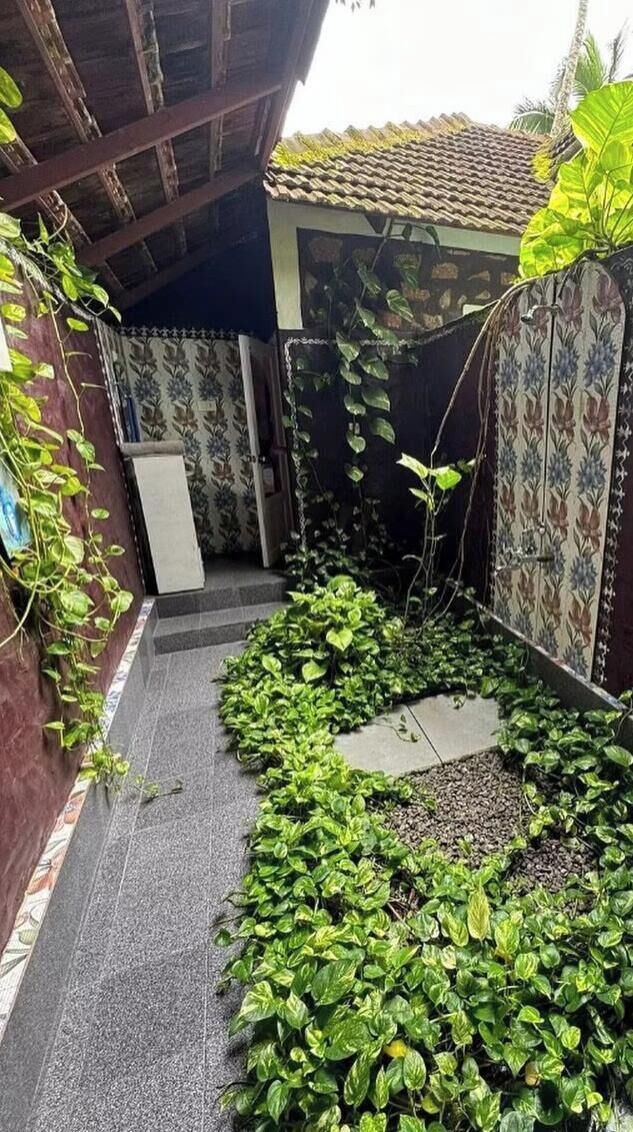 A courtyard with a tiled roof, a staircase, and a variety of plants.