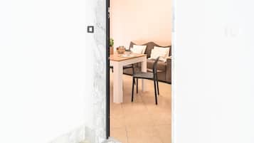 A room with a dining table and chairs, a sofa, and a small plant on the table.