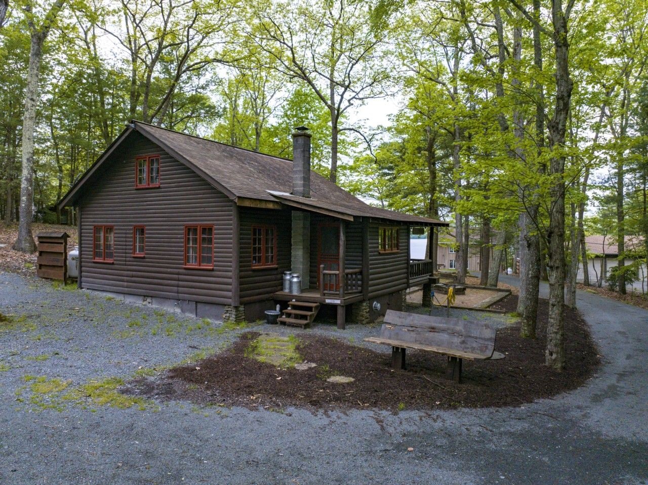 A rustic cabin with a porch, a chimney, and a small deck area.