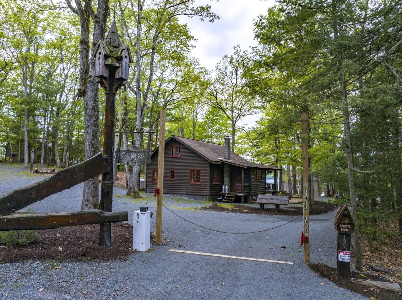 A rustic cabin with a porch, surrounded by trees.
