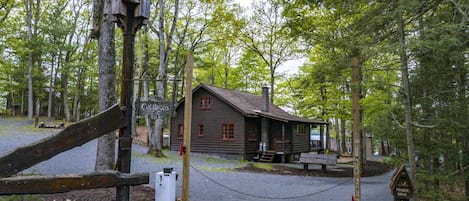 A rustic cabin with a porch, surrounded by trees.