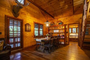 Ein Interieur einer Holzhütte mit Essbereich, Holzböden und einem aufgehängten Tierkopf.