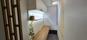 A narrow hallway with a wooden bench, a potted plant, and a shelf with a plant. - Decorated corner near the beach in Jardim Camburi (Vitória)