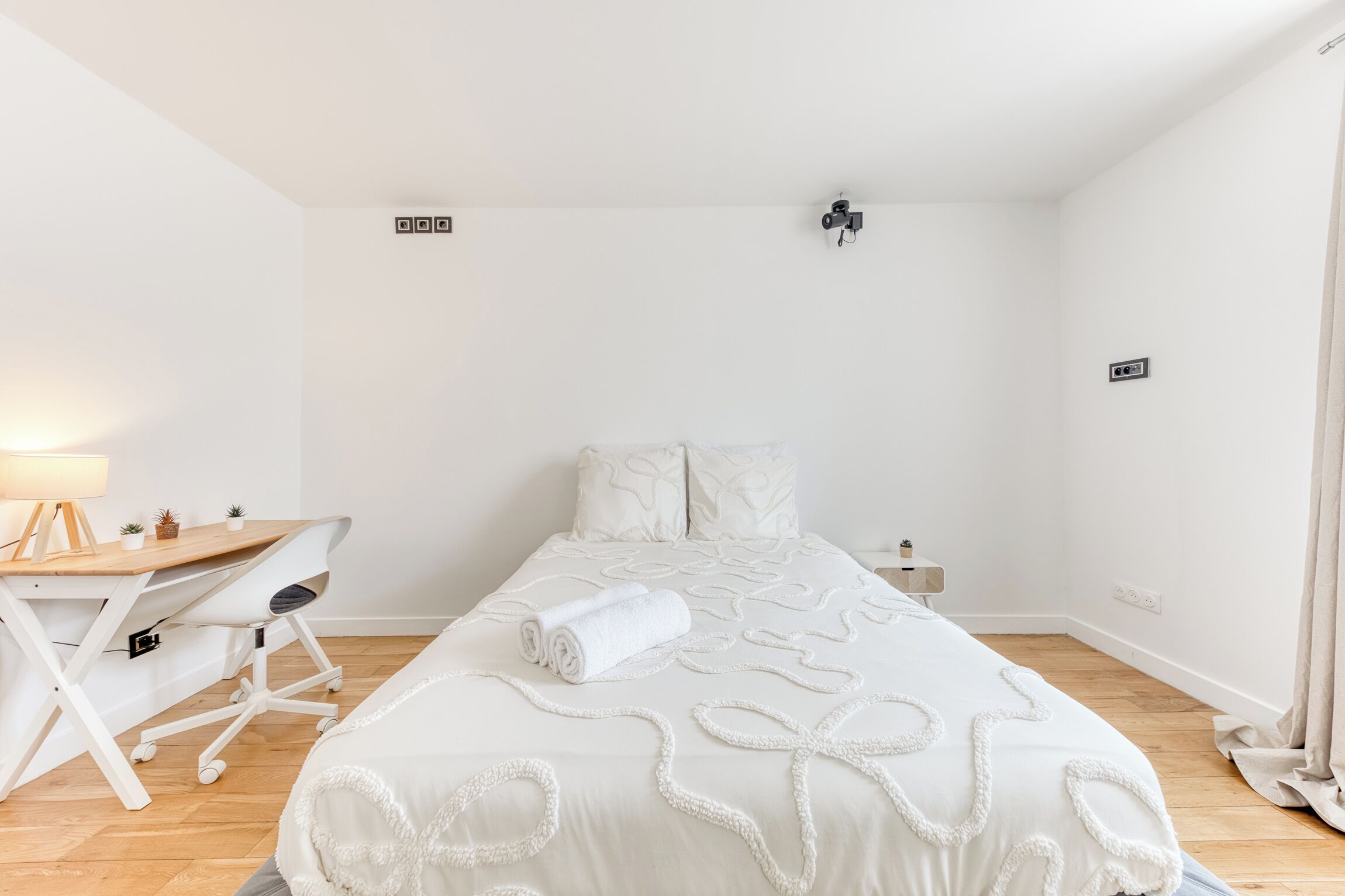 Un dormitorio minimalista con cama, escritorio y silla.