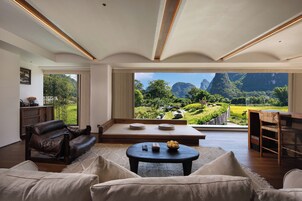 Una sala de estar moderna con un amplio ventanal que ofrece vistas a un paisaje montañoso.