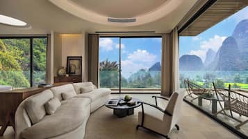 Una sala de estar moderna con un sofá curvo, una mesa de centro y vistas a un paisaje montañoso a través de amplios ventanales.