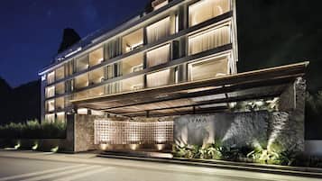 Un hotel de varios pisos con diseño moderno, que destaca por su entrada con fachada de piedra y un letrero que dice 'ZYMA YANGSHUO'.
