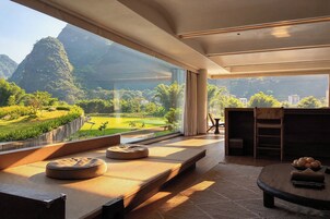 Un interior moderno con un amplio ventanal que ofrece vistas de un paisaje exuberante y montañas.