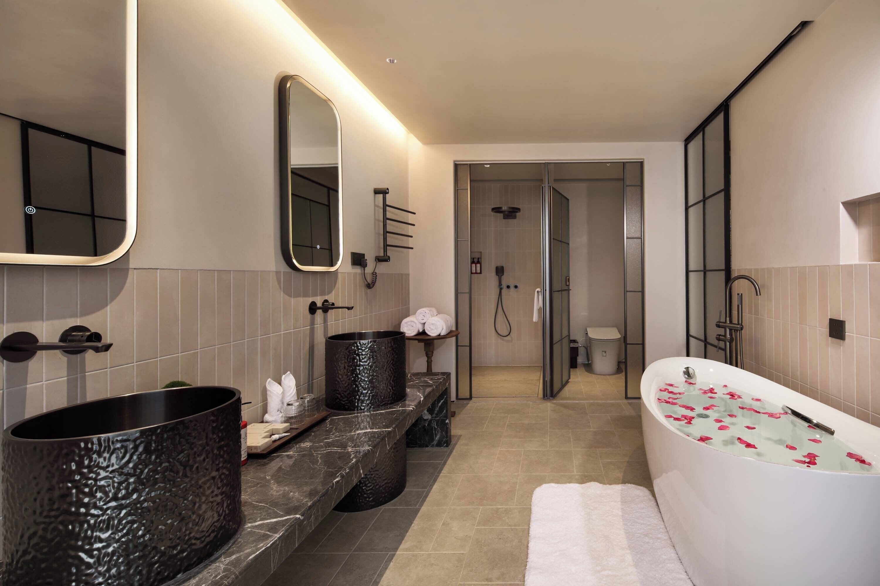 A modern bathroom with a large bathtub, a separate shower area, and a vanity with a large sink.