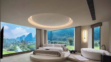 Une chambre à coucher moderne avec un lit aux lignes courbes, une grande baignoire et une vue sur un paysage montagneux.