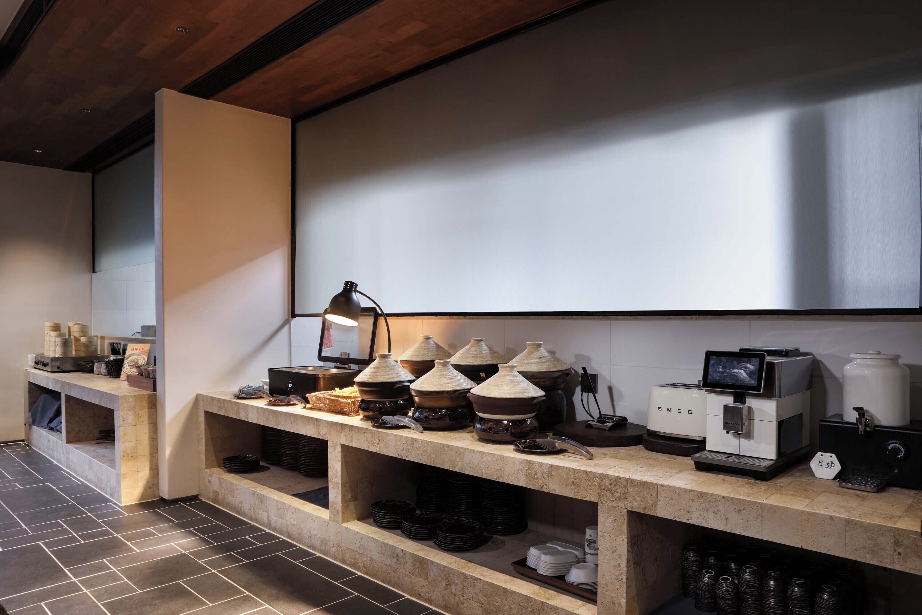 A kitchen area with a long counter, various kitchen appliances, and storage shelves.