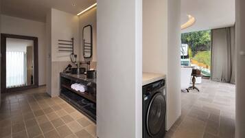 A modern laundry room with a washing machine, a drying rack, and a mirror.