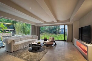 Una sala de estar moderna con un sofá, un sillón, una mesa de centro y un televisor de pantalla plana.