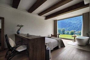 A modern bedroom with a large window, a bathtub, a desk, and a chair. - BYMA Valley Hideaway Resort Yangshuo·Ten-Mile Gallery · Yulong River·Double-Level Cliffside Infinity Pools (Guilin)