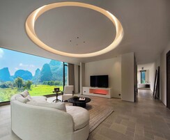 Una sala de estar moderna con un ventanal grande, un sofá, una mesa de centro, un televisor de pantalla plana y una lámpara circular.