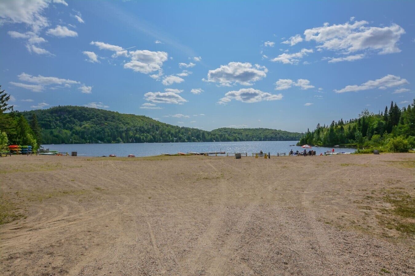 A beach with a dirt path leading to the water, surrounded by trees and hills.