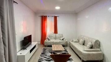 A modern living room with a sofa, a coffee table, and a TV on a stand.