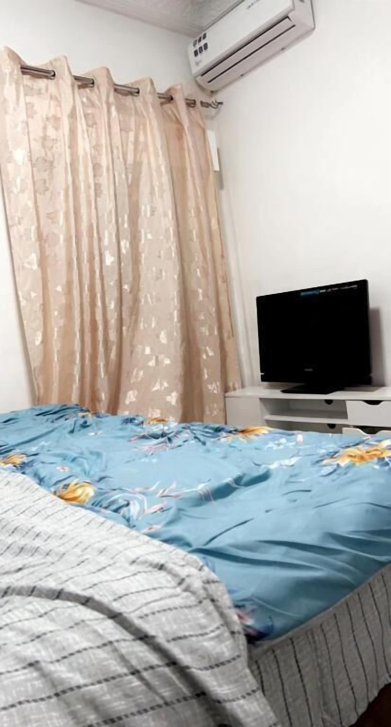 A bedroom with a bed, a television, and an air conditioning unit.