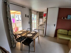 Ein Essbereich mit Tisch für vier Personen, einer Küchenzeile und einem grünen Sofa.