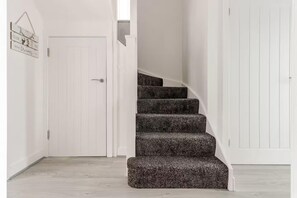 A staircase with carpeted steps leading to a white door.