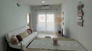 A modern living room with a sofa, a dining table, and a TV.