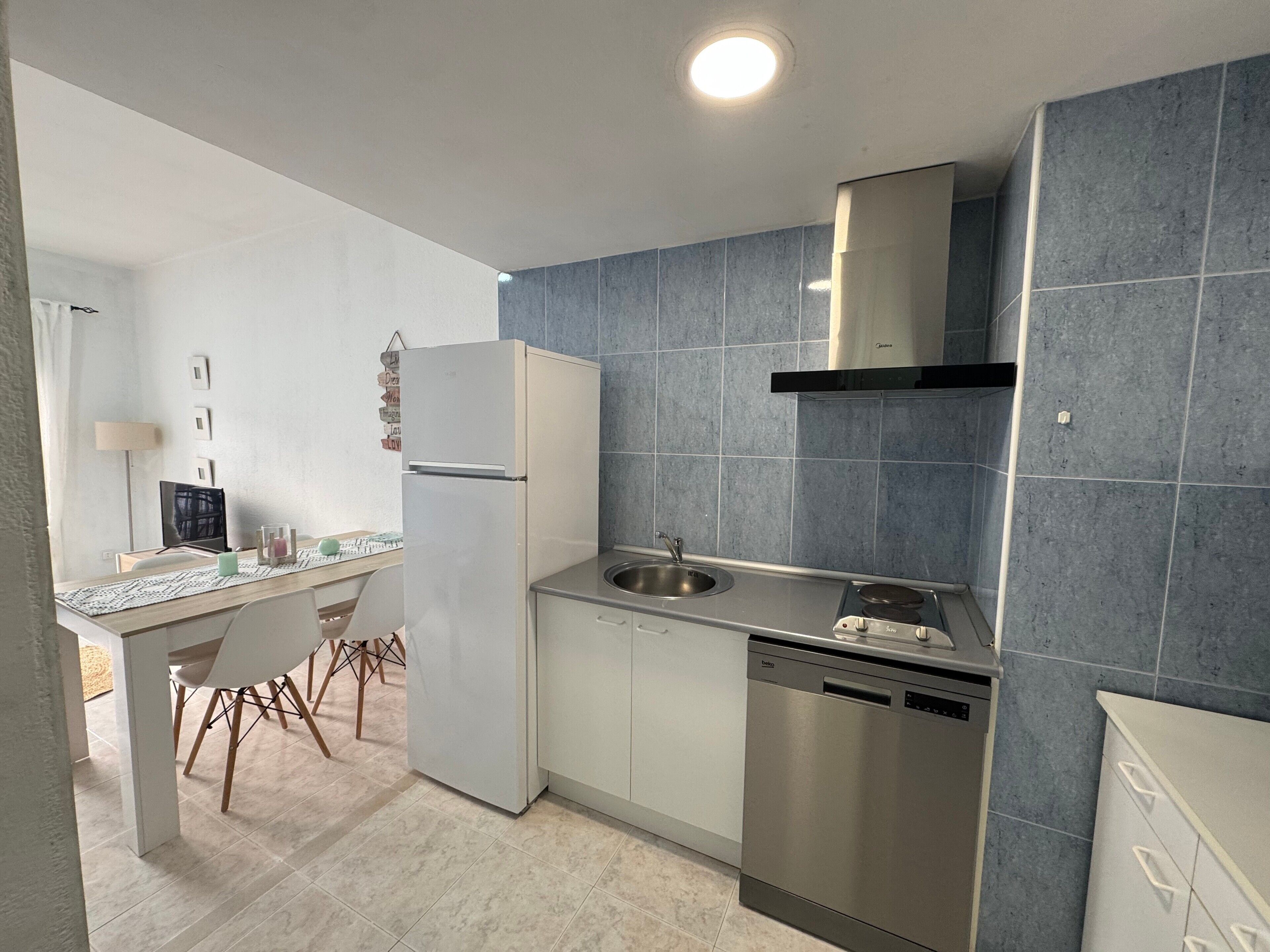 A modern kitchen with a built-in dishwasher, a stainless steel sink, and a refrigerator.