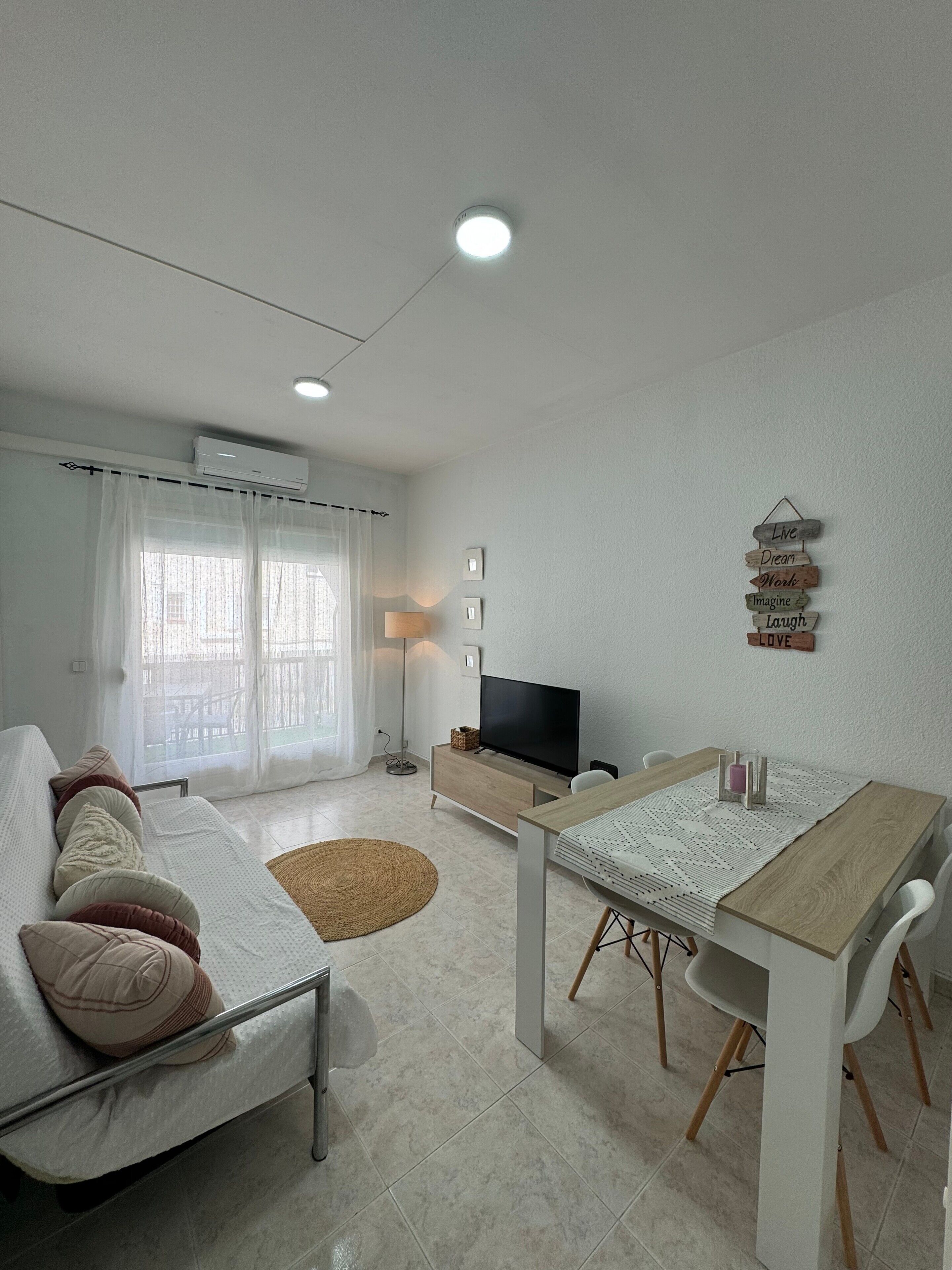 A modern living room with a sofa, a dining table, and a television.