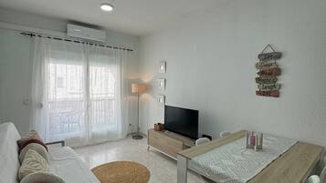 A modern living room with a sofa, a dining table, and a television.