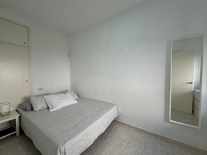 Ein Schlafzimmer mit einem Bett, einem Nachttisch, einem Spiegel und einem Kleiderschrank.